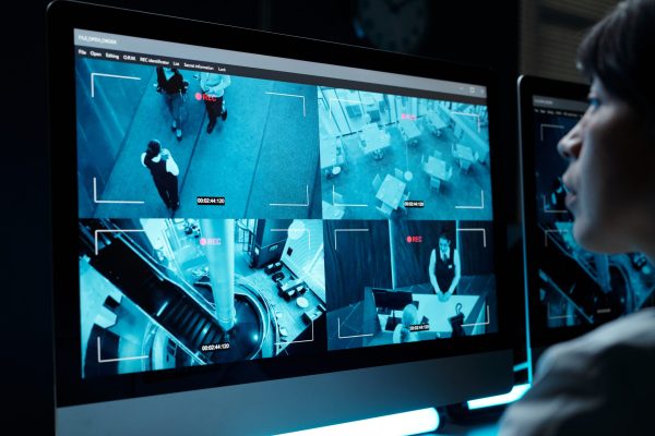 Screen of desktop computer with cctv video from every floor of modern hotel with staff working and clients or travelers with baggage