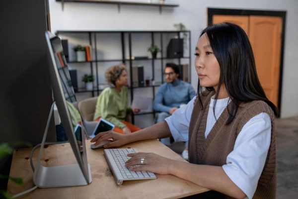 Young Asian businesswoman in casual clothes working in front of computer monitor fully stack email campaign